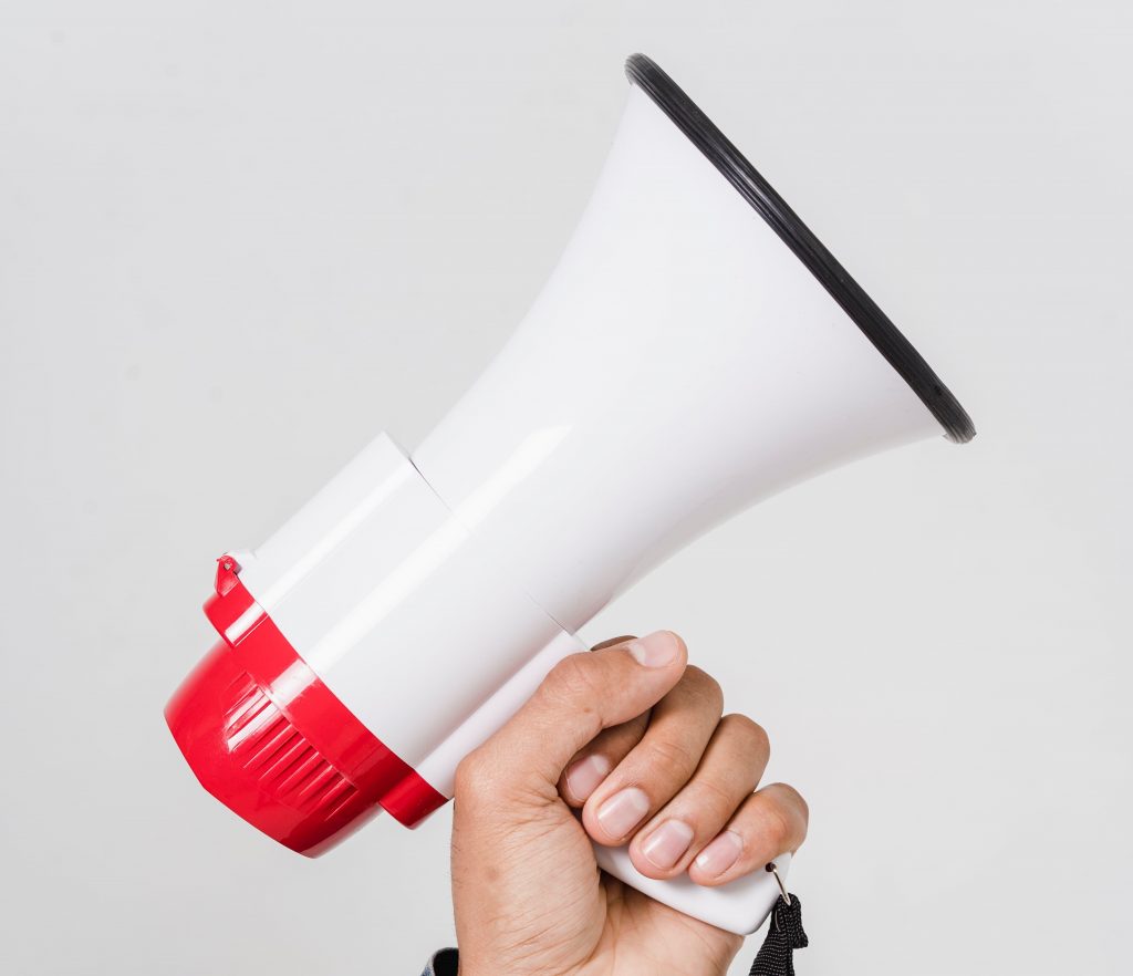 Eine Hand reckt ein Megafon in die Höhe. Das Megafon soll CTAs in Sozialen Medien repräsentieren.