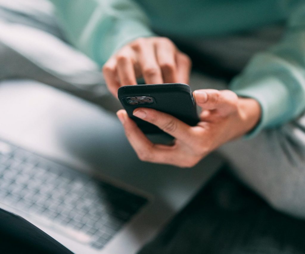 Eine Frau sitz mit Laptop und Smartphone im Schneidersitz. Eine durchdachte Omnichannel-Strategie ist entscheidend, um Ihre Patienten auf möglichst diversen Kanälen anzusprechen.