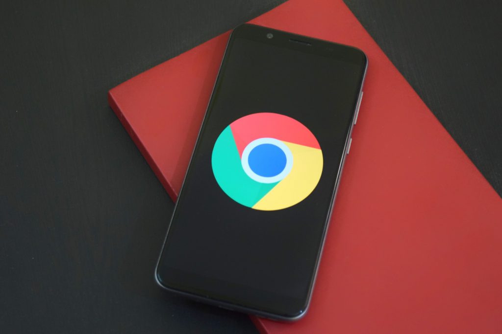 Zu sehen ist ein Smartphone, auf dem Display ist das Google Chrome-Symbol auf schwarzem Hintergrund abgebildet, um die Bedeutung Mobile Optimierung für die SEO zu verdeutlichen.